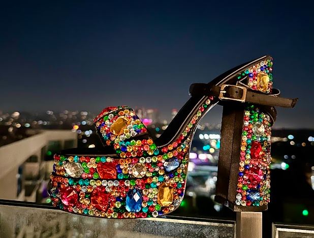 Open toe platform heels with colorful rhinestone embellishment in front of a city skyline