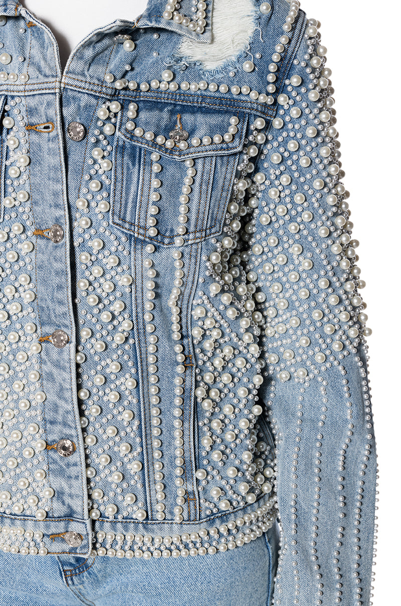 detail shot of denim statement jacket with distressing below the collar and pearl embellished accents all over the jacket