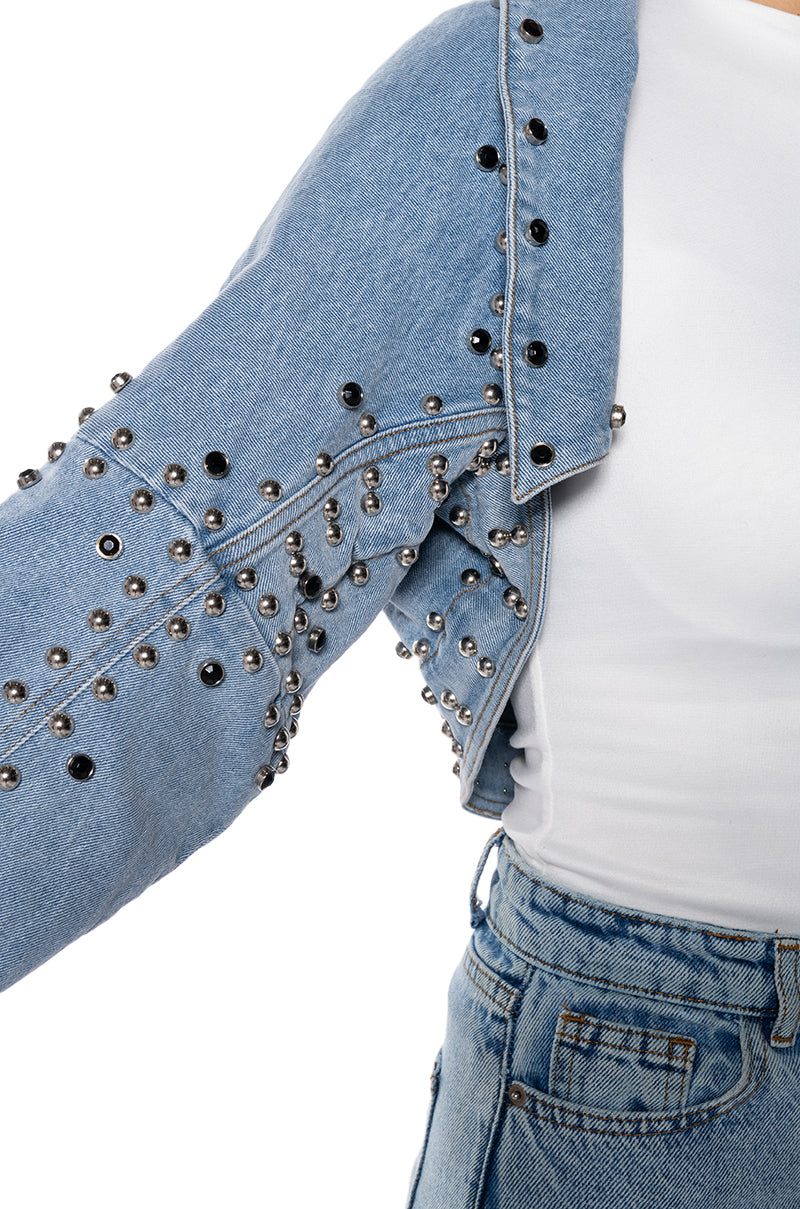 detail shot of light wash denim ultra cropped jacket with circular stud accents lining the seams