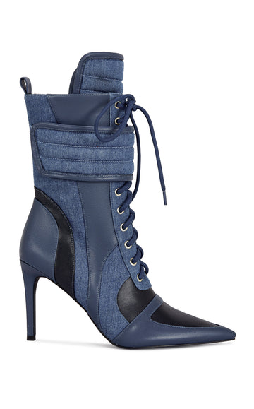 dark wash denim and navy blue faux leather heeled boots with a mid calf length, lace up accent, and velcro belted accent with an inner zip up closure