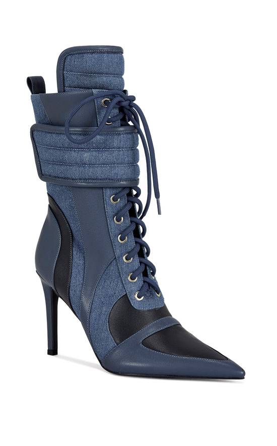 dark wash denim and navy blue faux leather heeled boots with a mid calf length, lace up accent, and velcro belted accent with an inner zip up closure