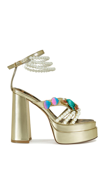 platform metallic gold faux leather statement heels with an open toe, pearl and shell embellishments on the upper, and an adjustable ankle strap with faux pearl draping