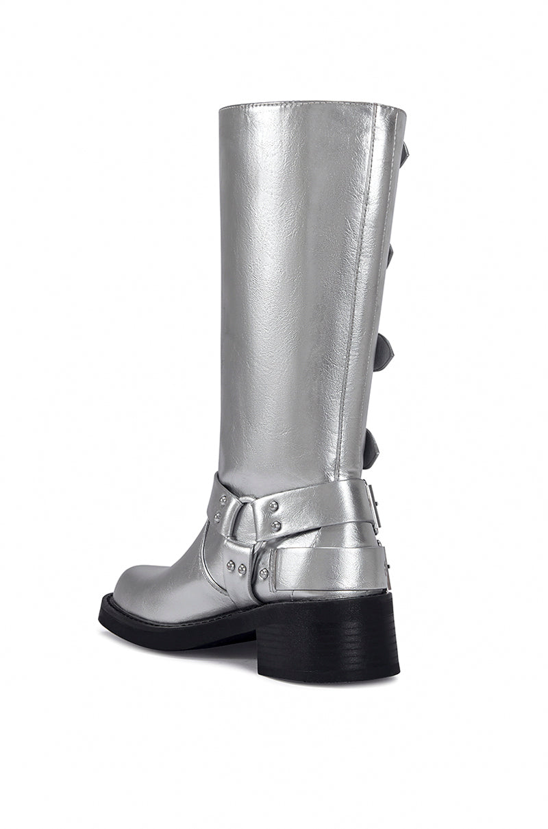 back view of side view of mid calf length metallic silver faux leather boots with a rounded toe, small block heel, and silver buckle design going up the shoe