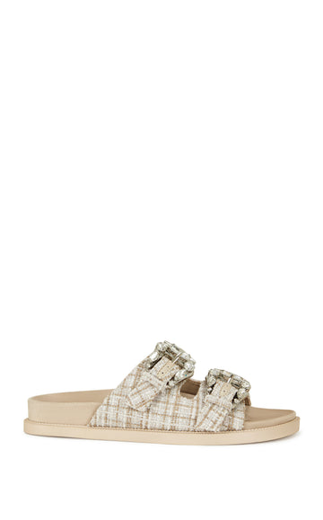 beige slip on flat sandal with a tweed upper with double straps featuring silver rhinestone studded belted accents on each strap