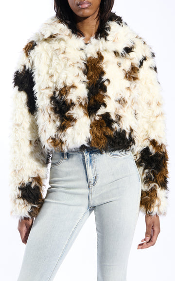 white, black, and brown cow printed faux fur statement jacket with a curly fur texture and a buttoned front closure