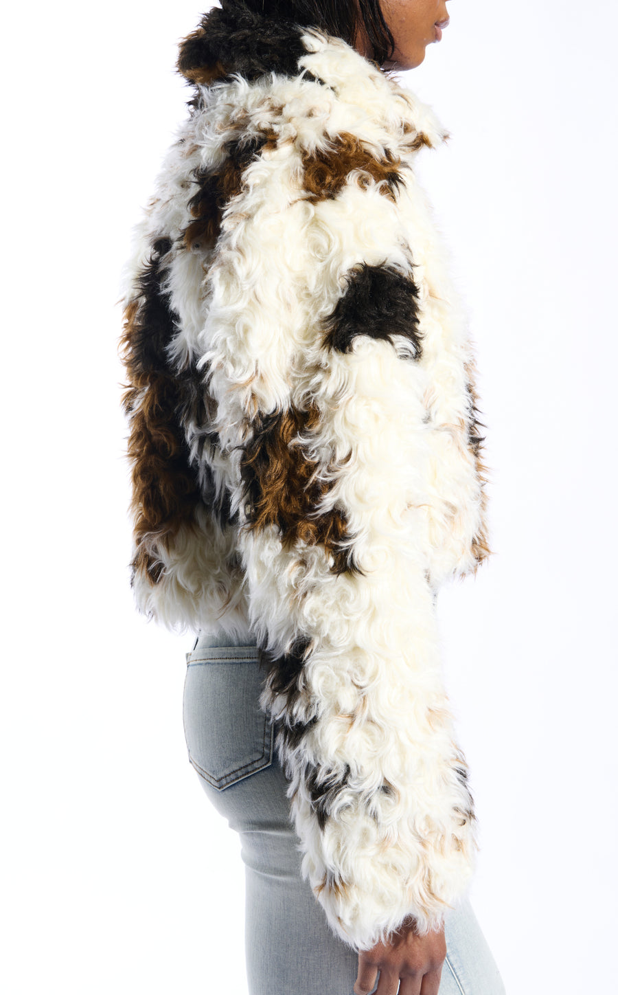 white, black, and brown cow printed faux fur statement jacket with a curly fur texture and a buttoned front closure