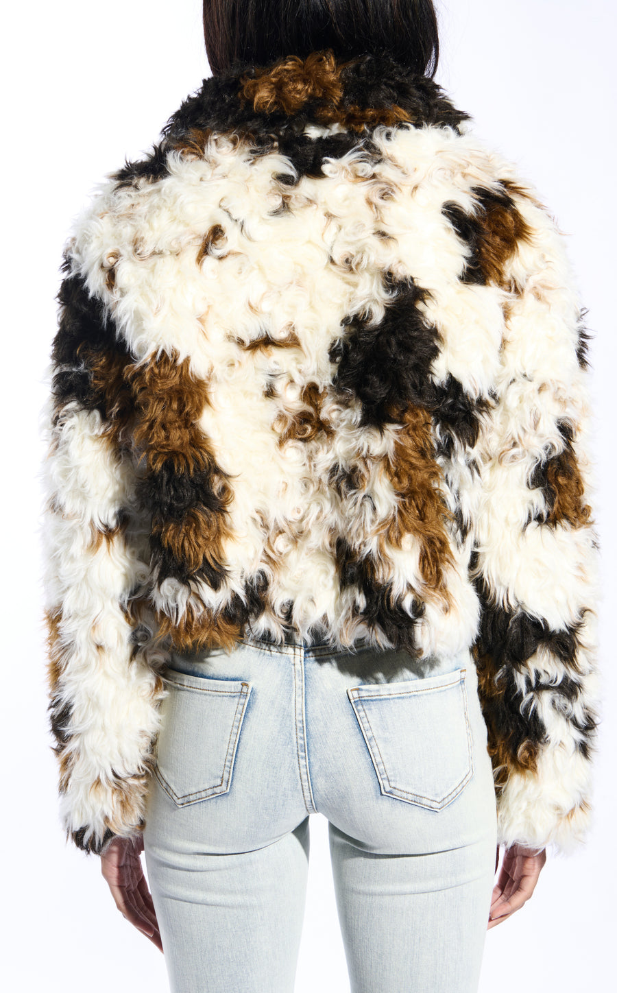 white, black, and brown cow printed faux fur statement jacket with a curly fur texture and a buttoned front closure