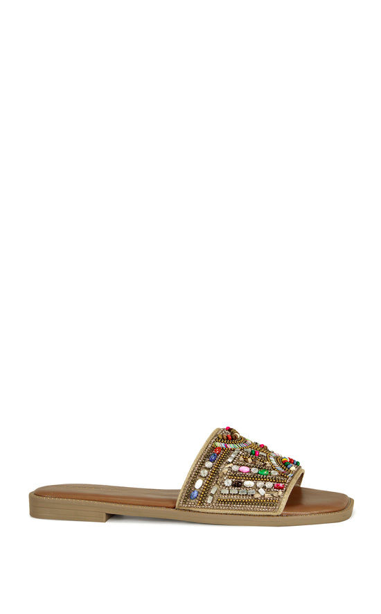beige faux leather slip on flat sandal with a colorful crystal embellished foot strap