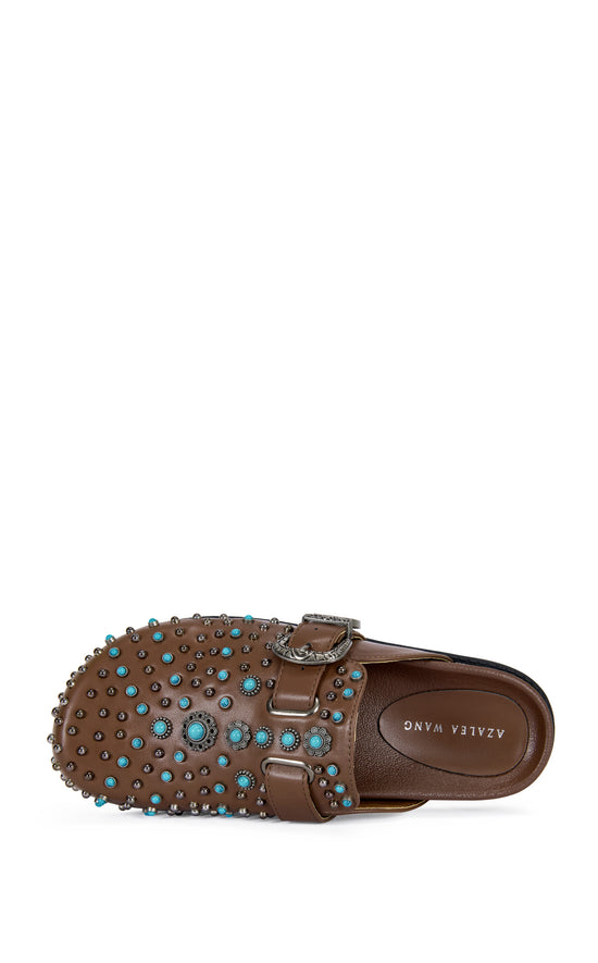 brown faux leather slip on flat mules with a western inspired belted accent with turquoise and stud embellishments