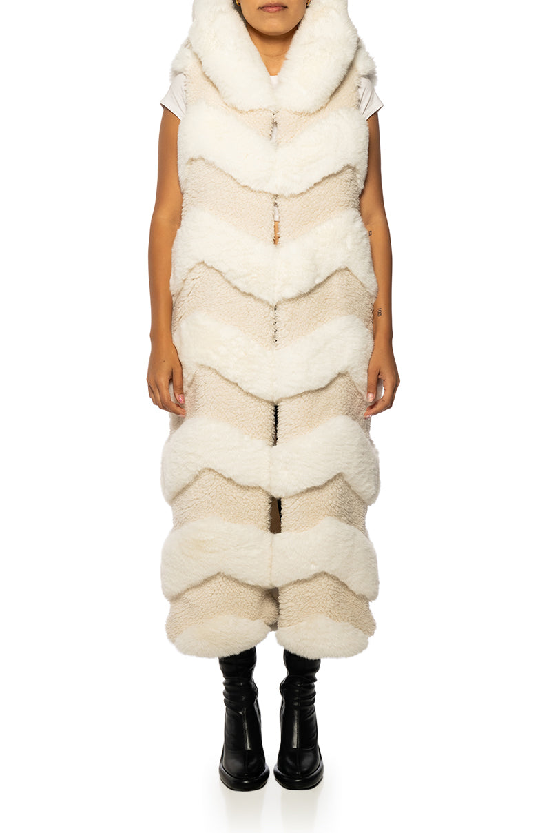 long trench style beige faux fur vest with a chevron fur pattern and a fluffy hood