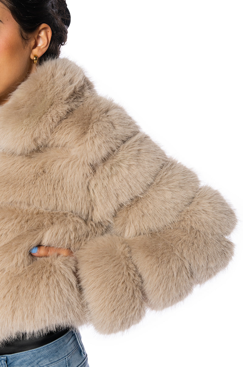 close up view of luxurious cropped zip up beige faux fur jacket with accent collar