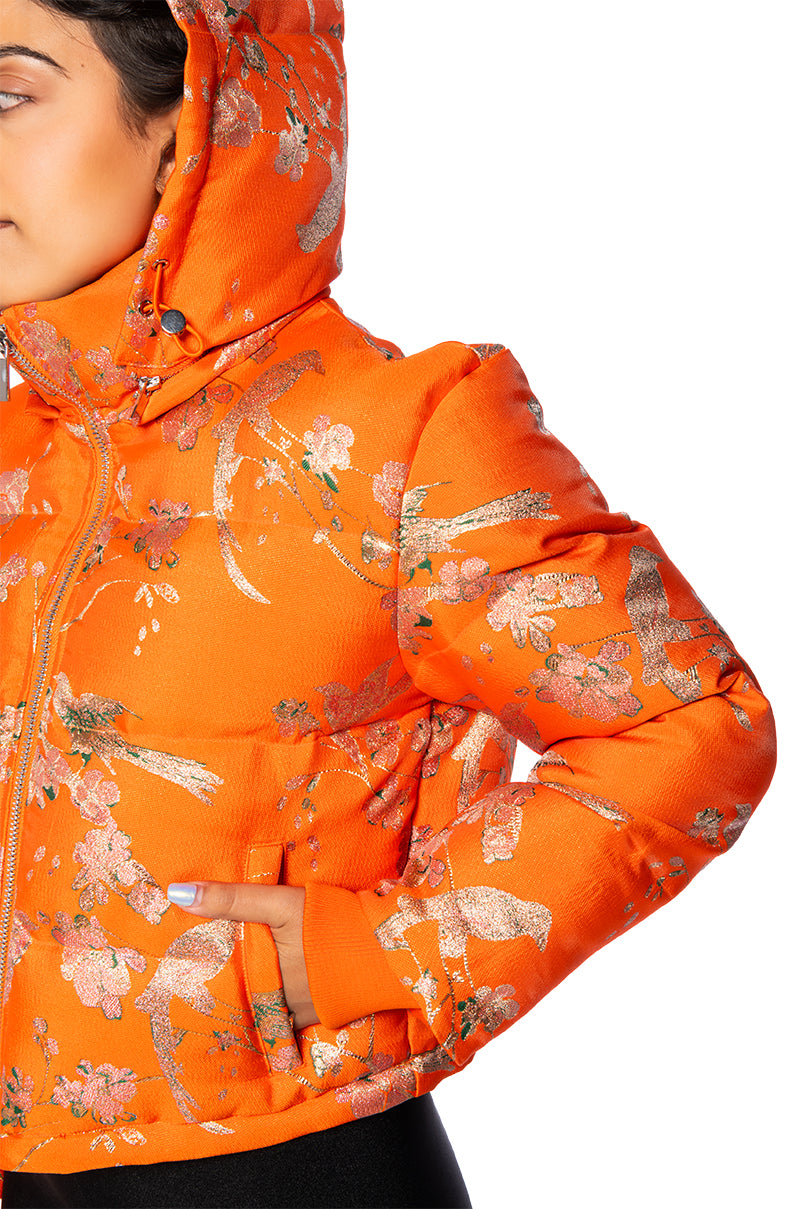 detail shot of bright orange cropped hooded puffer jacket with floral patterned design