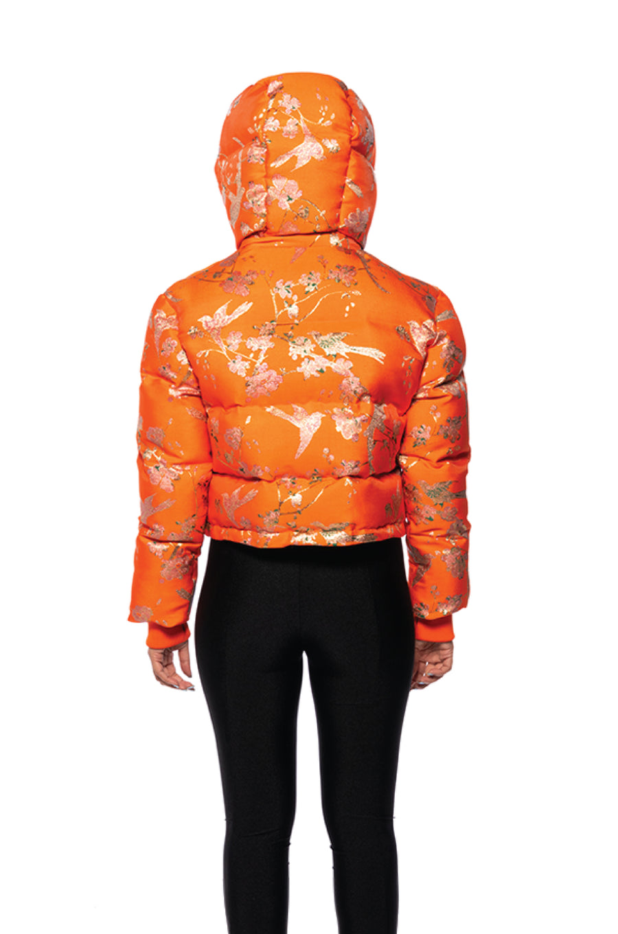back view of bright orange cropped hooded puffer jacket with floral patterned design