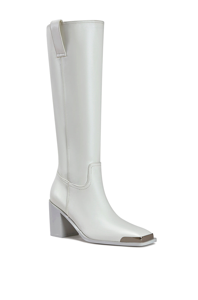 angled view of white faux leather western inspired riding boot with a silver hardware toe accent and a block heel