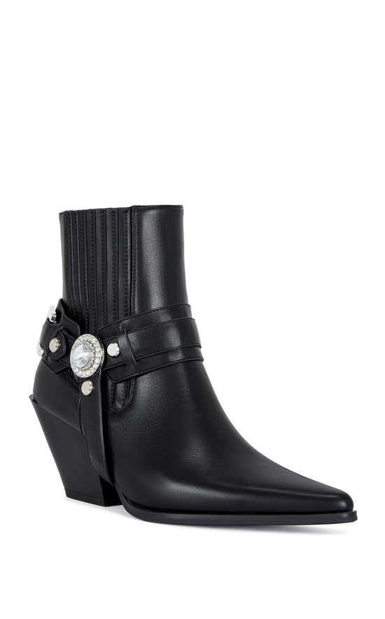 black faux leather ankle bootie with a pointed toe, block heel, and a belted accent on the upper with a chunky rhinestone embellishment
