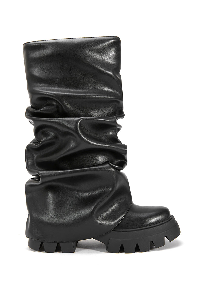 side view of black faux leather platform boots with a mid calf length and black fold over silhouette
