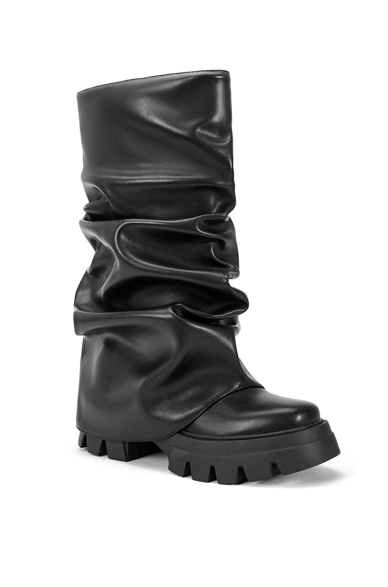 angled view of black faux leather platform boots with a mid calf length and black fold over silhouette