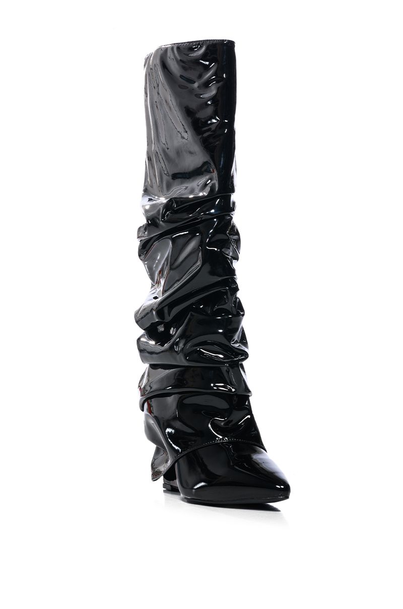 angled view of shiny black patent faux leather wedge boots with a ruched detail and fold over silhouette