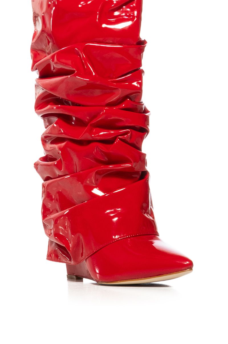 detail shot of shiny red patent faux leather wedge boots with a ruched detail and fold over silhouette