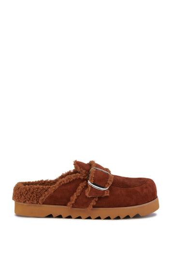 cozy chestnut brown faux suede statement mules with a ridged sole and faux sherpa lining inside the shoe. Finished with a silver buckle belted accent