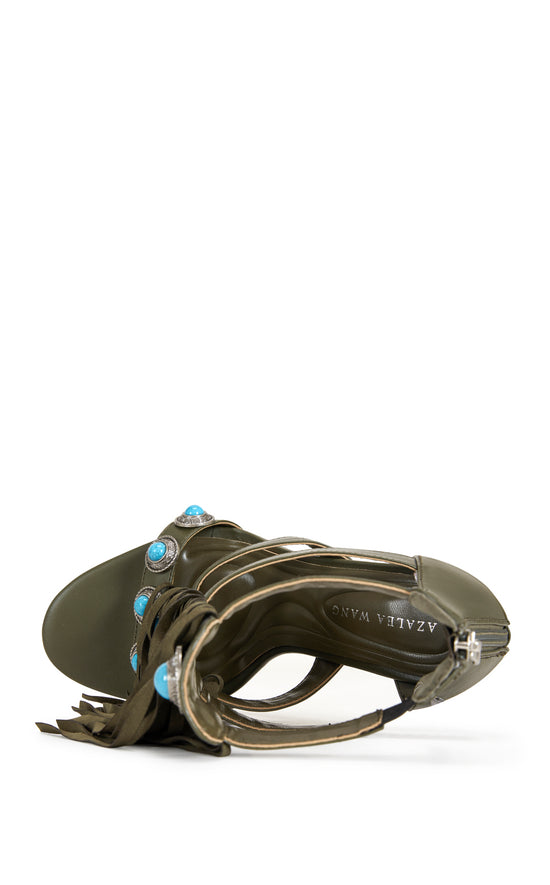 green faux leather strappy open toe sandals with a stiletto heel, and a green upper featuring faux suede fringe and turquoise studded embellishments, and a zip up closure on the ankle