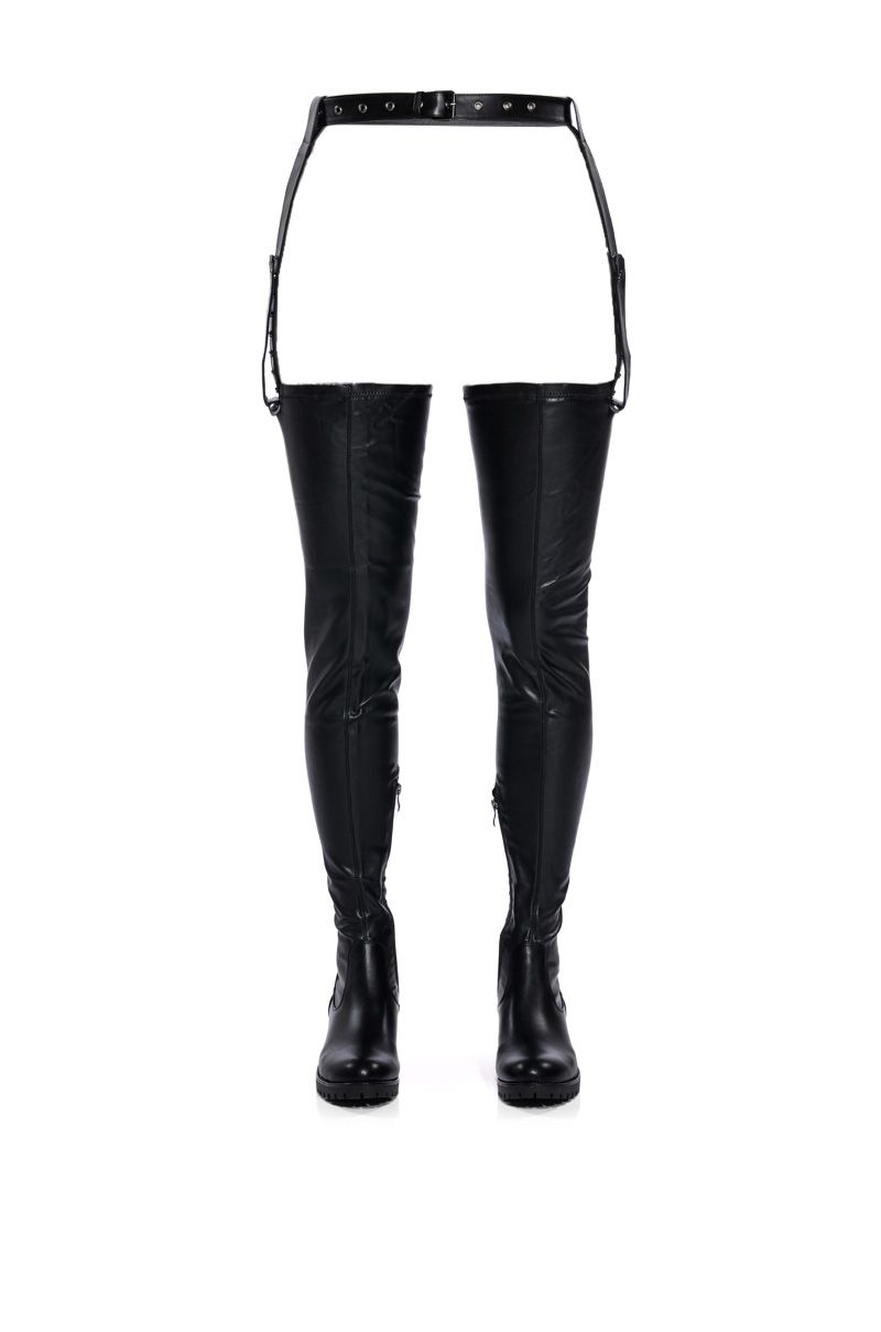 front view of black faux leather 4 way stretch thigh high flat boots with an attached stirrup belt 