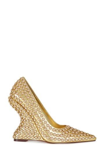 gold faux leather statement pumps with a structured wedge heel, pointed toe silhouette, and gold studs all over the shoe