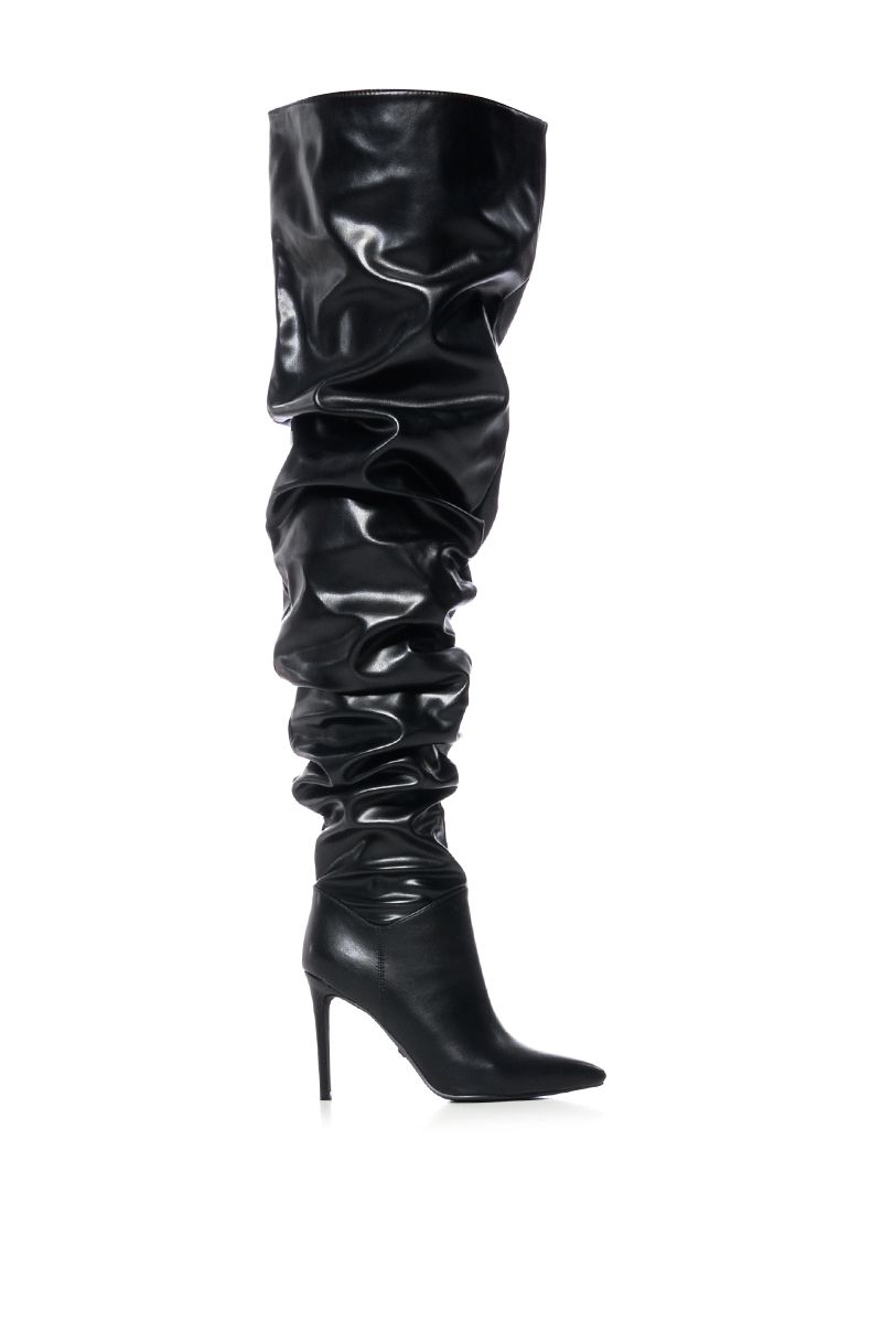 side view of black faux leather over the knee stiletto boots with a pointed toe and ruched detail