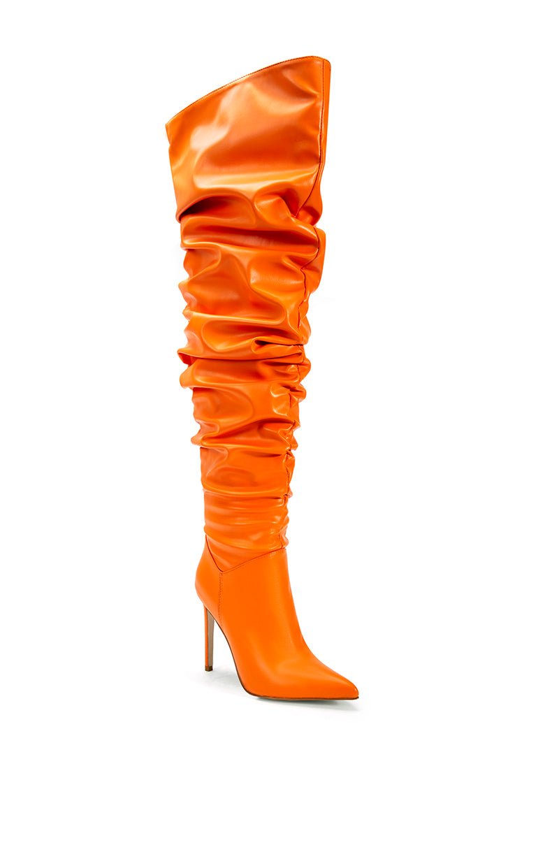angled view of orange faux leather over the knee stiletto boots with a pointed toe and ruched detail