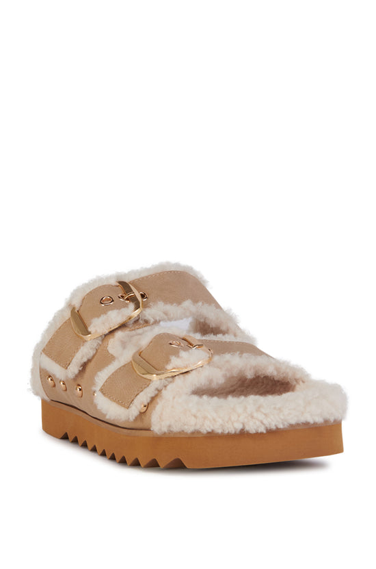 beige slip on sherpa lined cozy sandals with gold hardware accents and a ridged sole