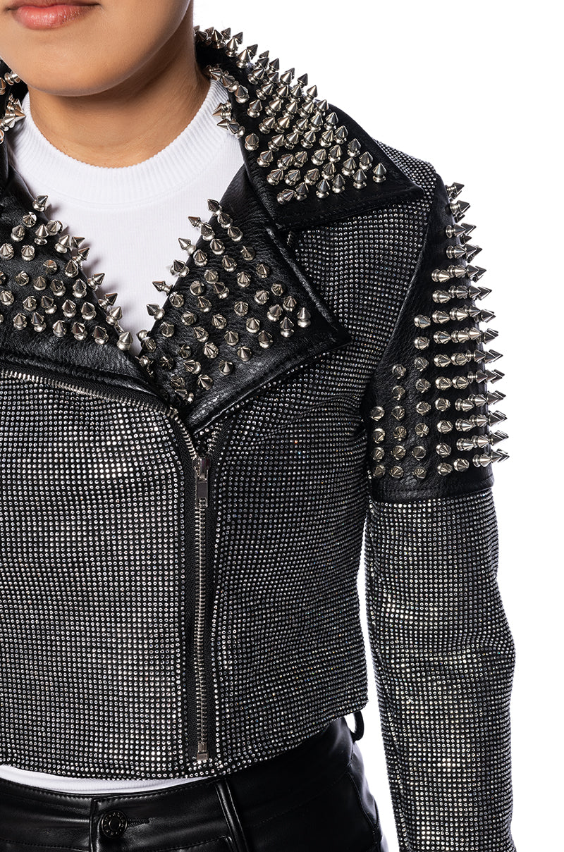detail shot of cropped black faux leather jacket with studded shoulders and collars and shiny crystal embellishments