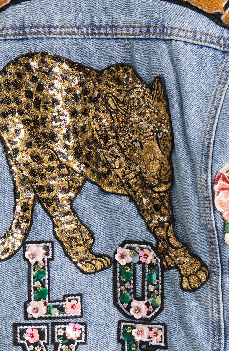 light wash denim jacket with button up closure and decorative patches on the sleeve and back of the jacket
