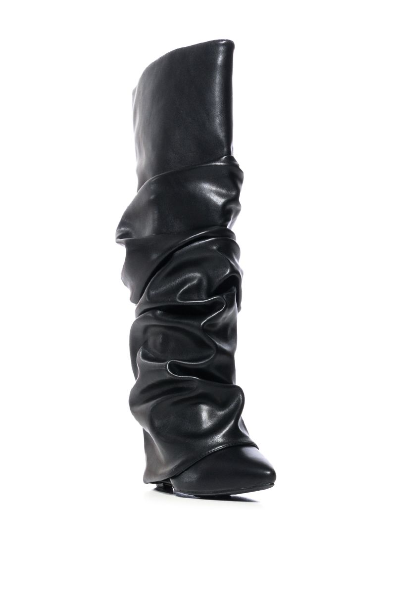 angled view of black faux leather wedge boots with a pointed toe and ruched fold over silhouette