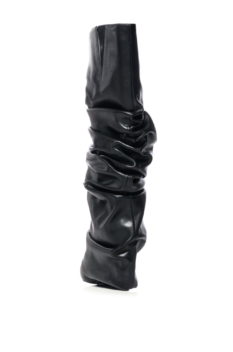back view of black faux leather wedge boots with a pointed toe and ruched fold over silhouette