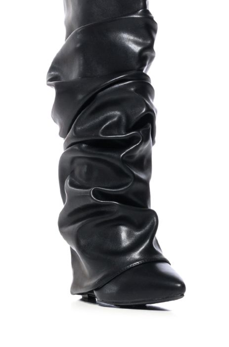 detail shot of black faux leather wedge boots with a pointed toe and ruched fold over silhouette
