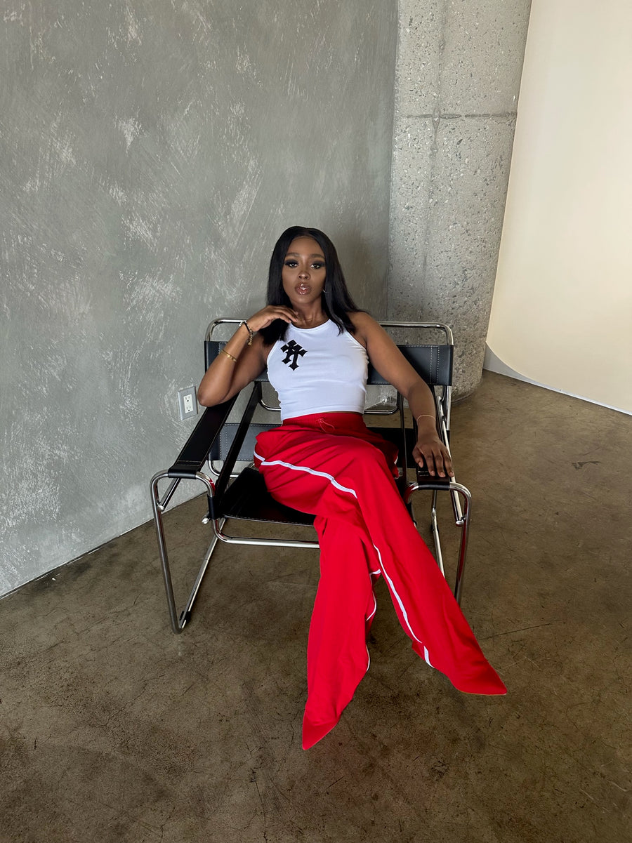 image of model sitting in a chair styled in white shirt and red statement track pant boots