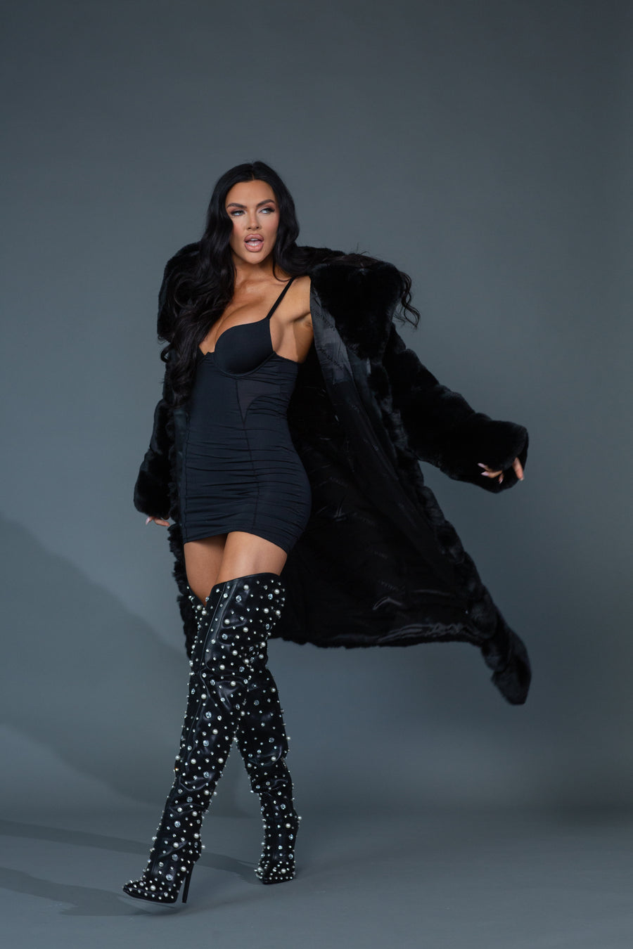 Model posing while wearing black faux fur trench coat