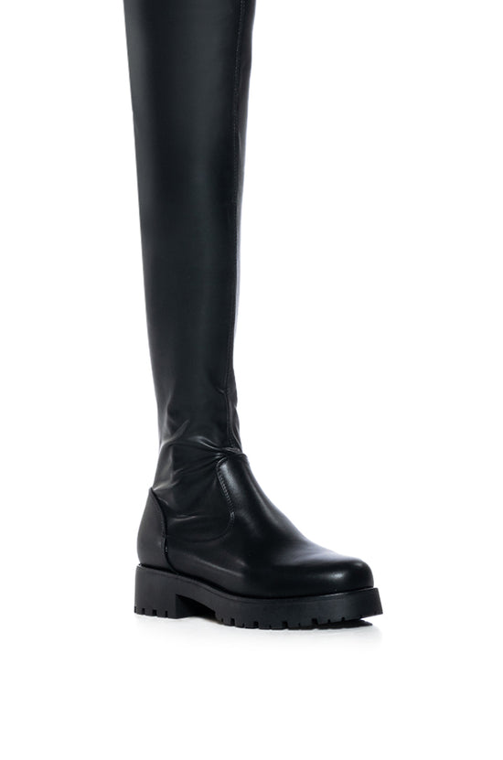 detail shot of black faux leather over the knee stretchy flat boot made with 4 way stretch material